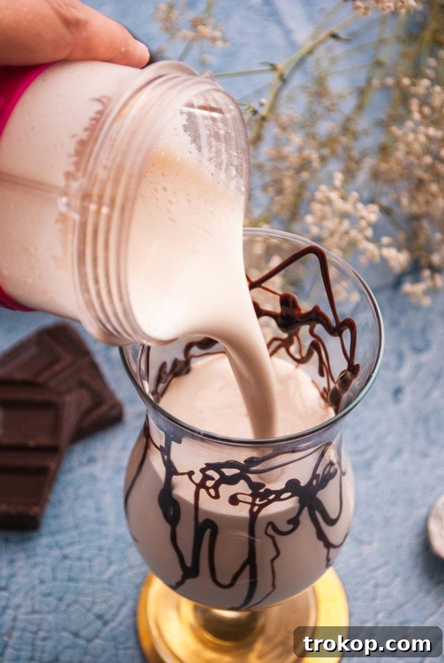 Bushwacker Recipe: Make Your Own Cream of Coconut Cocktail 6 Carefully pouring the freshly blended Bushwacker cocktail into a hurricane glass adorned with chocolate syrup.