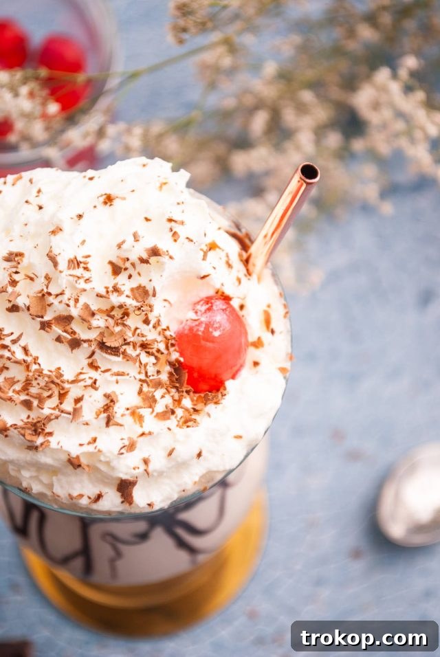Bushwacker Recipe: Make Your Own Cream of Coconut Cocktail 7 A perfectly garnished Bushwacker cocktail topped with rich whipped cream, delicate grated dark chocolate, and a bright red maraschino cherry, ready to be enjoyed.