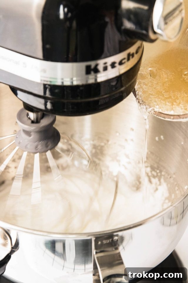 Silky Smooth Italian Meringue Buttercream Frosting 6 Hot sugar syrup being carefully drizzled into whipping meringue in a stand mixer for Italian buttercream.
