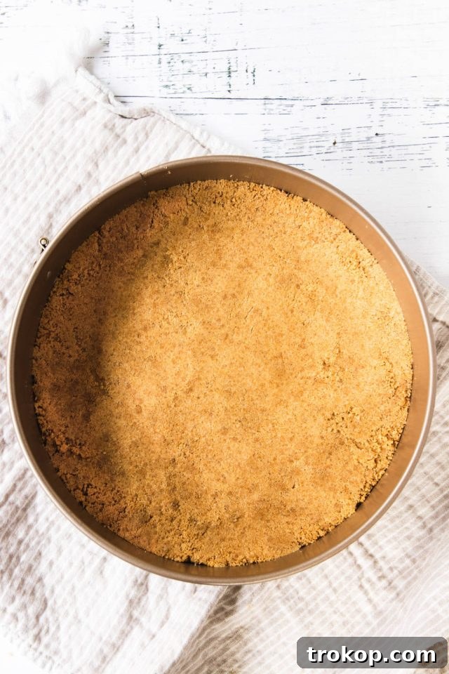Decadent Baked Caramilk Cheesecake 5 Pressing graham cracker mixture into the bottom of a springform pan for the Caramilk Cheesecake crust
