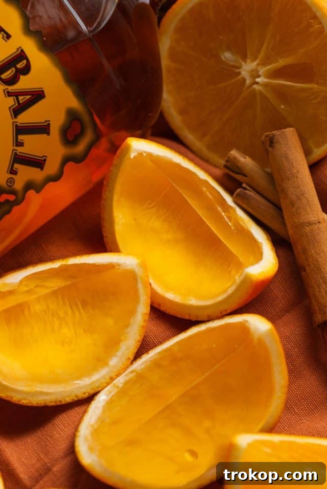 Spicy Fireball Jello Shots served in hollowed orange rinds, with cinnamon sticks.