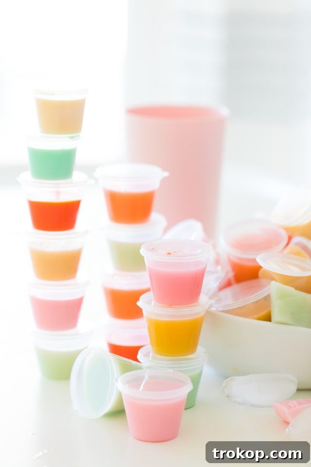 A collection of classic jello shots in small plastic cups, ready for a party.