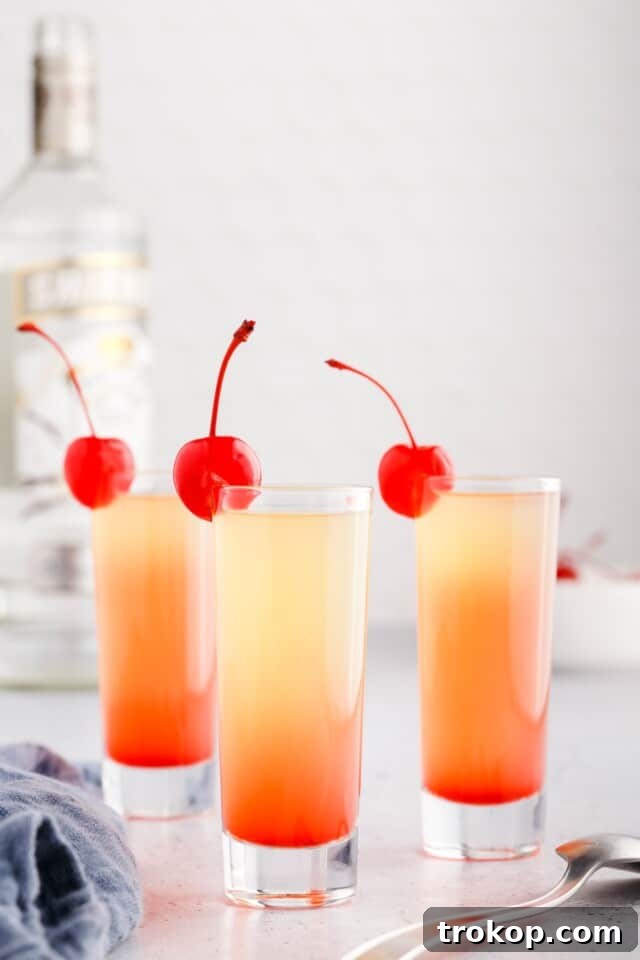 A Pineapple Upside Down Cake Shot, perfectly layered with a cherry on top.
