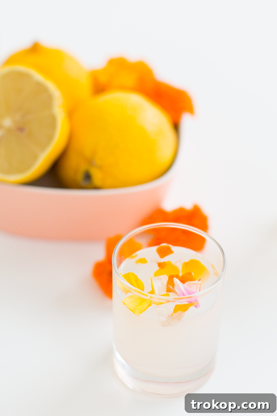 An elegant Edible Flower Lemon Jello Shot, featuring delicate flowers suspended in clear lemon gelatin.