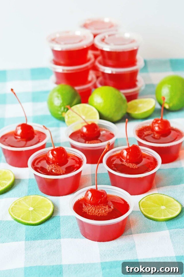 Vibrant Cherry Limeade Jello Shots garnished with lime slices, evoking a sense of sweet and sour nostalgia.