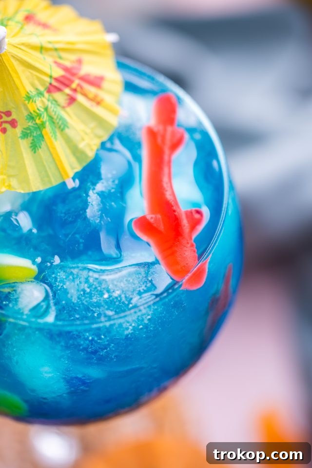 Close-up of the Fish Bowl Drink showing Swedish Fish gummies nestled among ice cubes in a large glass, highlighting its fun presentation.