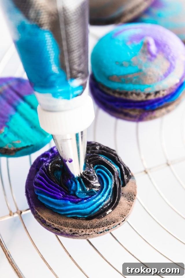 Cosmic Macaron Delights 12 Swirling the colorful buttercream frosting onto the back of a macaron shell, ready for assembly.