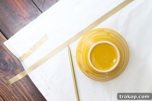 Craft Your Own Scalloped Tablecloth 4 Close-up of essential materials: a light-colored drop cloth, sharp scissors, a pencil, and a ceramic bowl, neatly arranged on a flat surface, demonstrating the simplicity of the DIY scalloped tablecloth project.