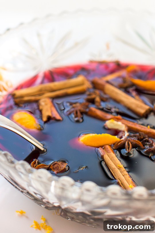 25 Easy & Festive Christmas Cocktails for Holiday Merriment 14 Hot Spice Mulled Wine Recipe for Christmas cocktail recipes, served in a mug with orange slices and cinnamon sticks.