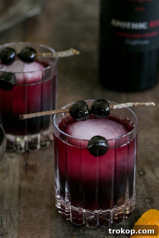 25 Easy & Festive Christmas Cocktails for Holiday Merriment 16 Holiday Manhattan for Christmas cocktail recipes, a dark red drink in a cocktail glass with a cherry.