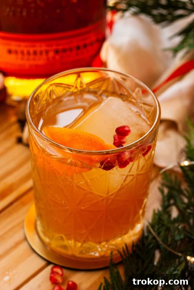 25 Easy & Festive Christmas Cocktails for Holiday Merriment 4 Christmas Old Fashioned cocktail in a single serving glass, garnished with an orange peel and a cherry.