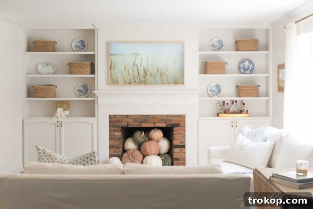 Decorative pumpkins inside an empty fireplace for fall decor.