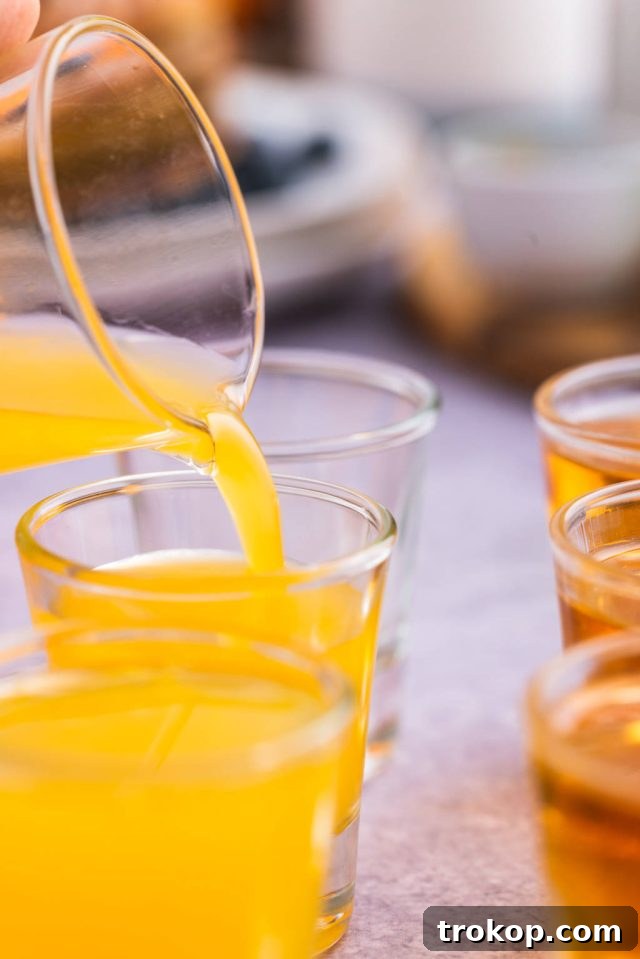 A shot glass filled with vibrant orange juice, ready to be served alongside the main Breakfast Shot.