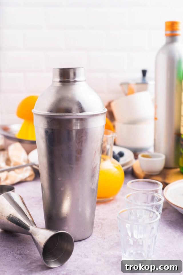 Various useful bar equipment, including a cocktail shaker, jigger, and shot glasses, essential for making the perfect Breakfast Shots.