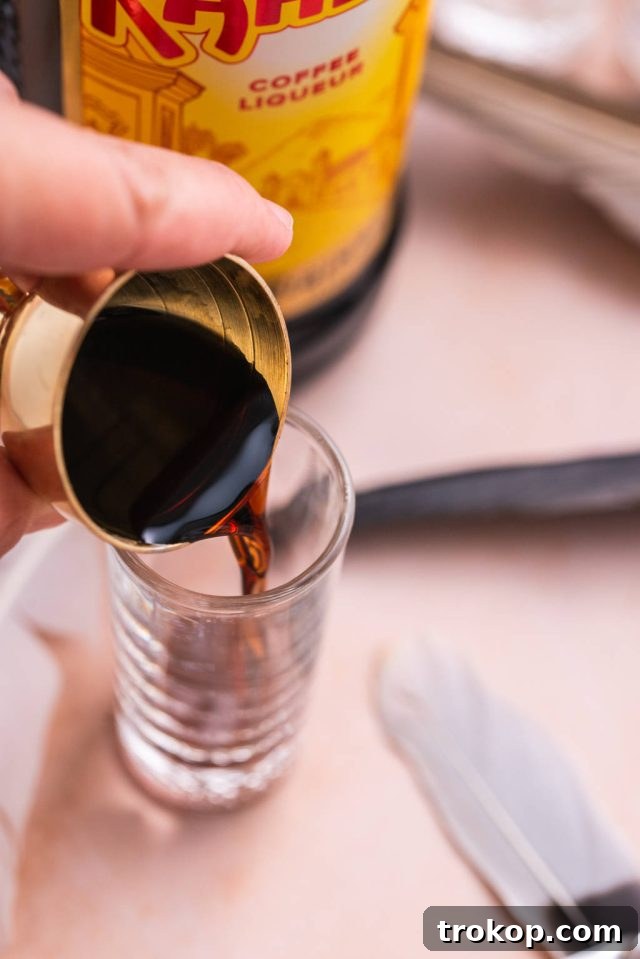 Crafting the Perfect Duck Fart Shot 6 Pouring the Kahlua coffee liqueur into a shot glass as the first layer using a jigger for precise measurement.
