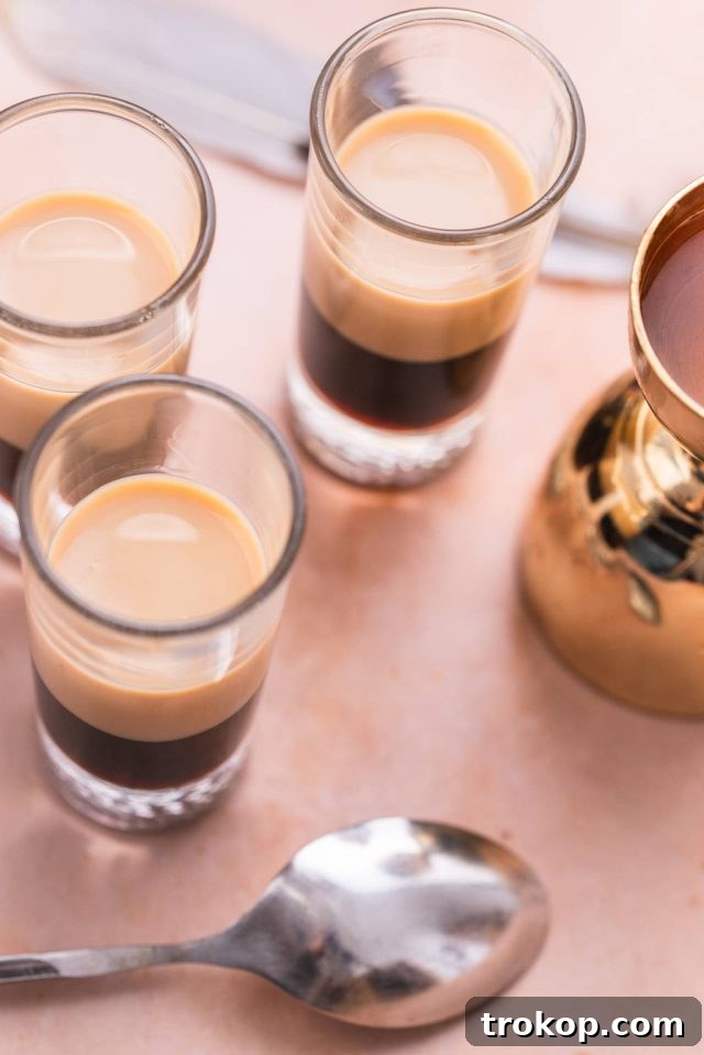 Crafting the Perfect Duck Fart Shot 7 Two distinct layers, coffee liqueur and Irish cream, formed in a shot glass, with a bar spoon next to it for the next layer.