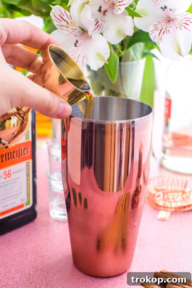 Pouring a liqueur into a cocktail shaker, illustrating the mixing process for the shot.