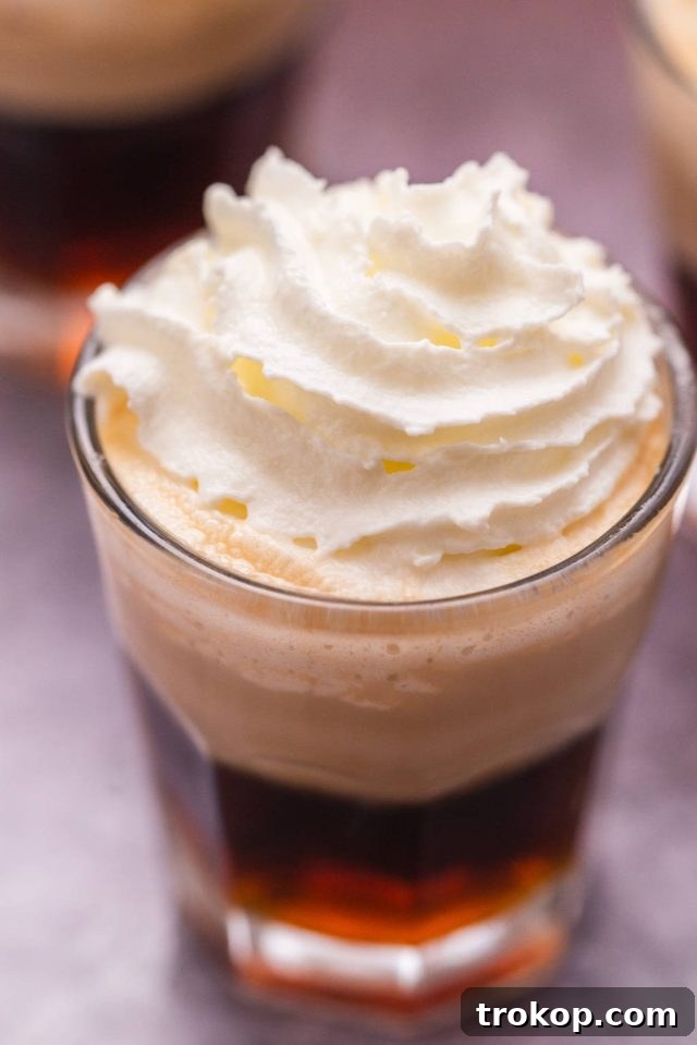 Close-up of a Blow Job Shot, showcasing the layered liqueurs and soft whipped cream topping.