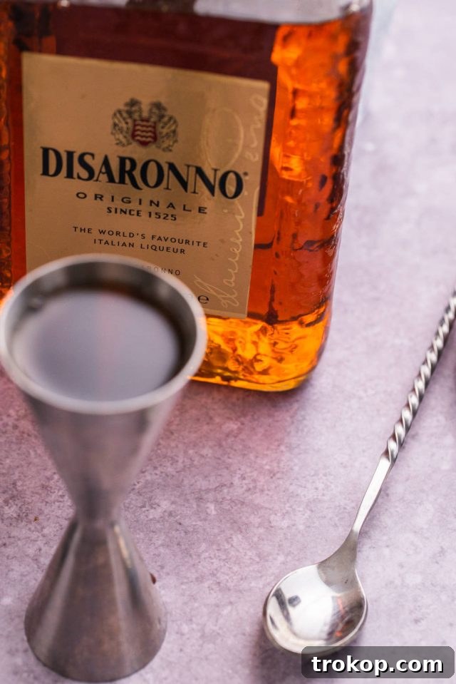 A bartender accurately measuring liqueurs into a jigger before adding them to a cocktail shaker.