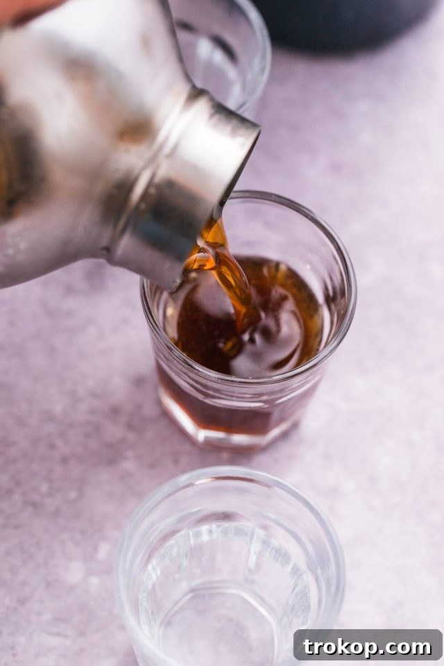 The blended Kahlua and Amaretto base being carefully poured into several shot glasses.