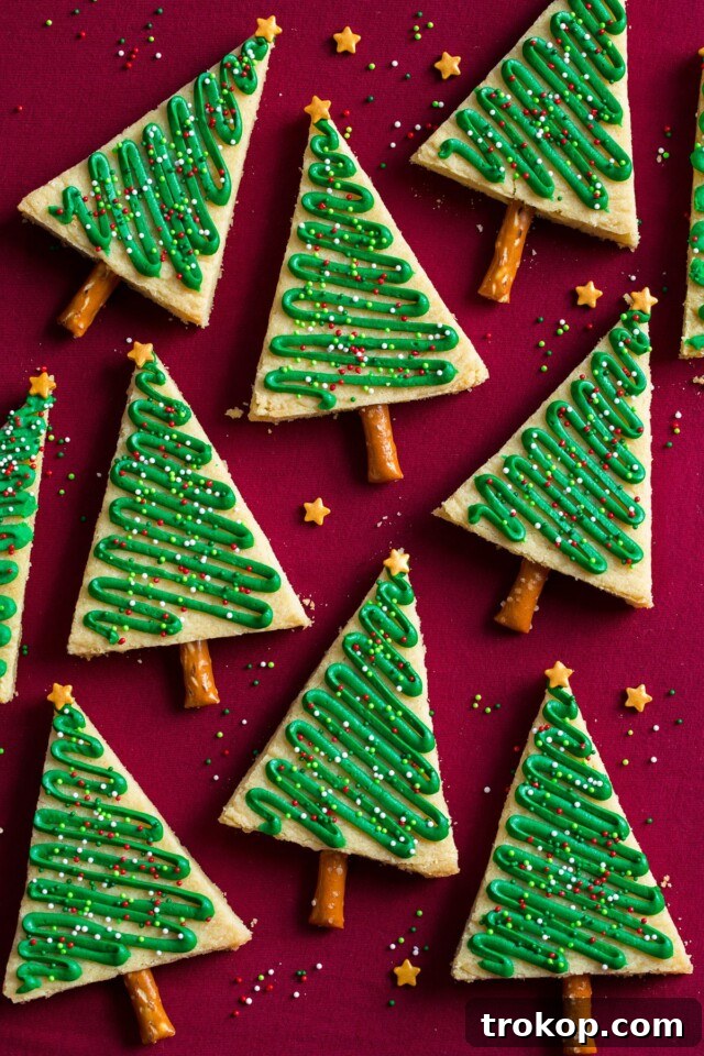 Holiday Cookie Masterclass: Recipes for Delicious Treats and Stunning Displays 27 Festive Frosted Christmas Tree Cookies, featuring a green frosted tree with sprinkles and a pretzel trunk.