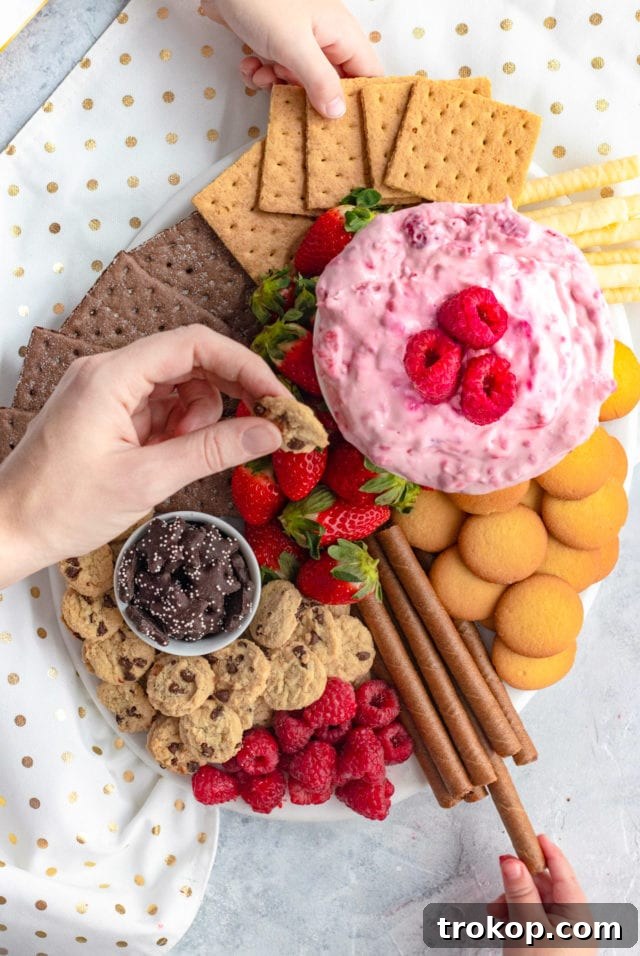 Creative Valentine's Day Party Concepts 17 Raspberry Cream Cheese Dip Recipe Dessert Board featuring various fruits, cookies, and a sweet dip.