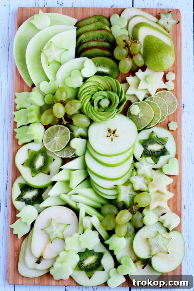 Brilliant Fruit Platter Ideas and Expert Presentation Tips 11 A monochromatic green fruit platter idea featuring honeydew melon, kiwi, green grapes, apples, pears, starfruit, lime, and a beautiful avocado rose centerpiece.