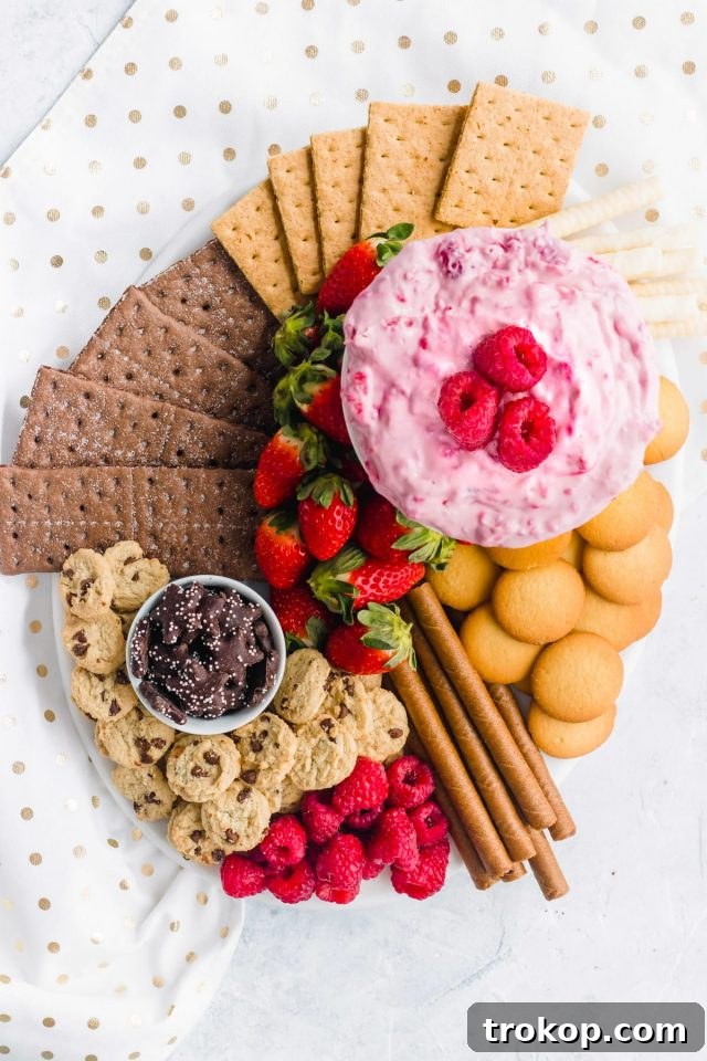 Brilliant Fruit Platter Ideas and Expert Presentation Tips 3 A dessert berry board featuring various berries like strawberries, blueberries, and raspberries, with a central bowl of creamy raspberry cream cheese dip.