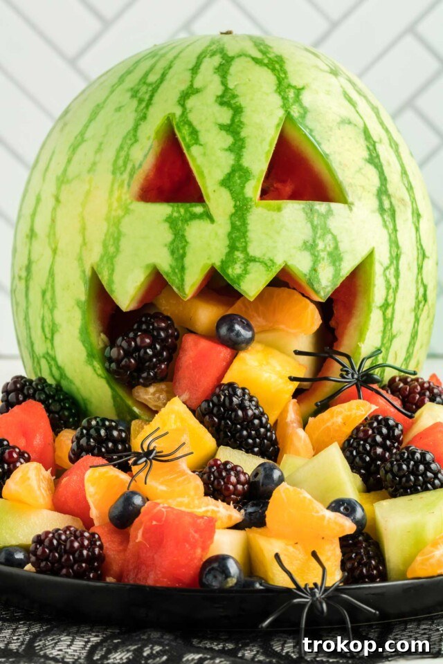 Brilliant Fruit Platter Ideas and Expert Presentation Tips 21 A festive Halloween fruit salad served in a carved watermelon jack-o-lantern, overflowing with fresh, colorful fruits.