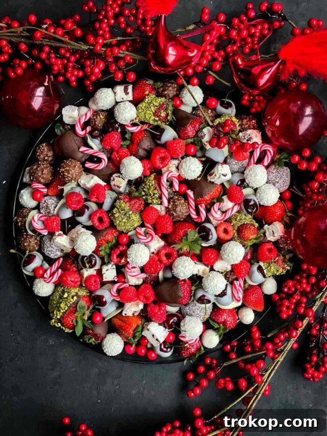 Brilliant Fruit Platter Ideas and Expert Presentation Tips 24 A festive Christmas fruit platter boasting a cheerful red and white color scheme, delightfully mixed with classic holiday chocolates and candies.