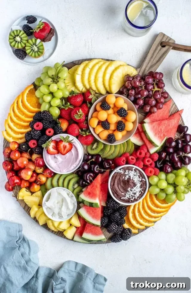 Brilliant Fruit Platter Ideas and Expert Presentation Tips 7 A fresh fruit board adorned with various colorful fruits like grapes, strawberries, kiwi, and melon, accompanied by a creamy strawberry yogurt dip.