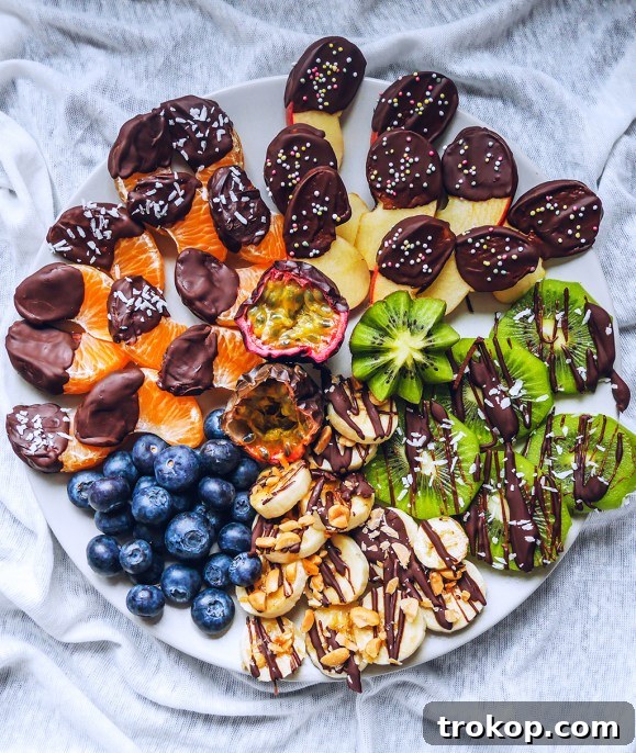 Brilliant Fruit Platter Ideas and Expert Presentation Tips 10 An indulgent chocolate dipped fruit platter featuring various fruits like strawberries and apple slices generously coated in melted chocolate and crunchy toppings.