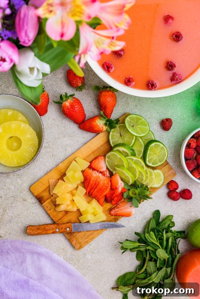 Spring Celebration Punch 5 A selection of fresh garnishes: pineapple chunks, vibrant strawberries, crisp lime slices, and fragrant mint leaves, ready to adorn your fruity Easter Punch by Ashley Rose of Sugar & Cloth.