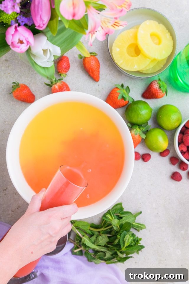 Spring Celebration Punch 7 The initial step of making Easter Punch, showing various liquids being combined in a large punch bowl by Ashley Rose of Sugar & Cloth.
