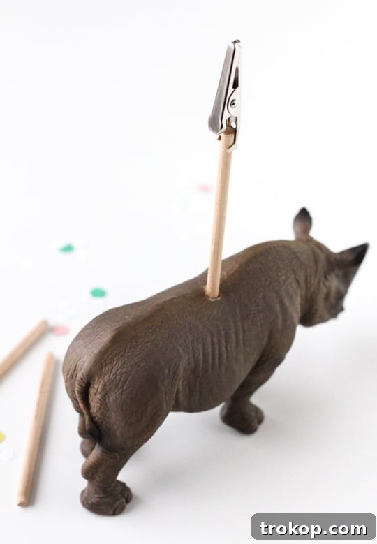 Applying super glue into the drilled hole on the animal figurine before inserting the dowel rod.