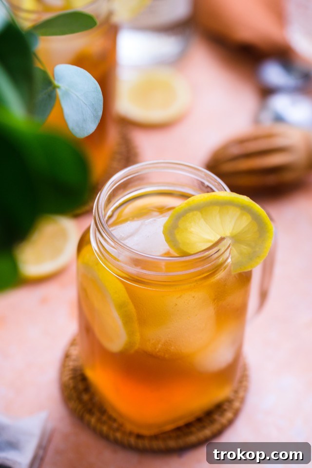 A Spiked Arnold Palmer in a glass next to a pitcher, ready for serving.