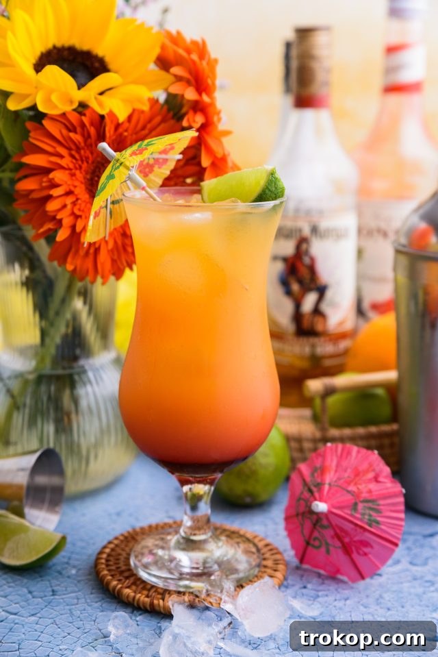Sunshine in a Glass Bahama Mama Recipe 2 Classic Bahama Mama cocktail in a hurricane glass, garnished with a lime wedge and a cocktail umbrella.