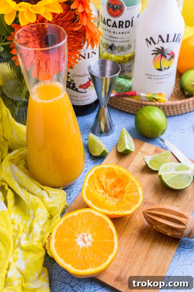 Sunshine in a Glass Bahama Mama Recipe 4 Assortment of fresh Bahama Mama ingredients including bottles of rum, fresh pineapple, oranges, and a lime.