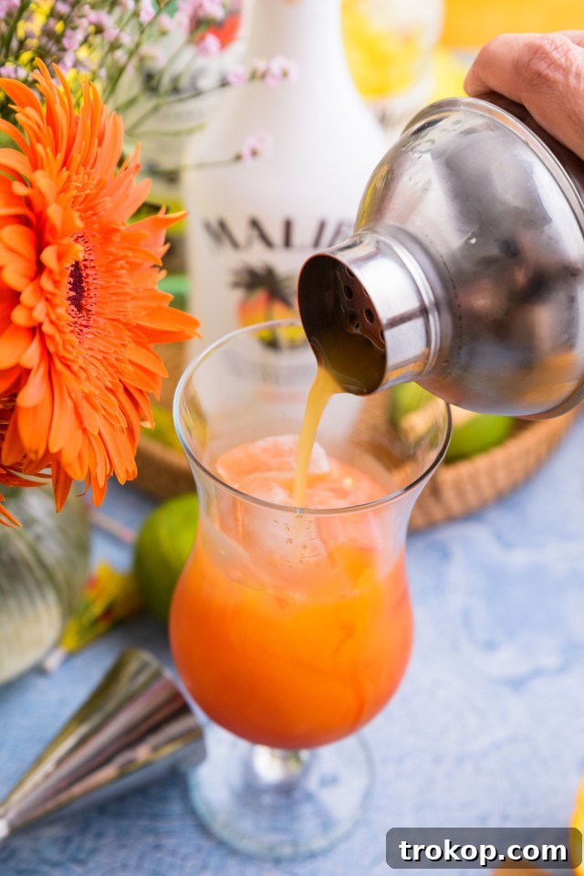 Sunshine in a Glass Bahama Mama Recipe 8 A Bahama Mama being strained from a cocktail shaker into a hurricane glass filled with ice.