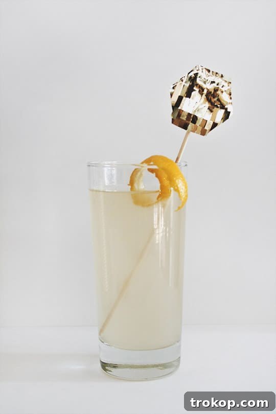 French 75 cocktail with a gold fringe stirrer on a festive table setting.