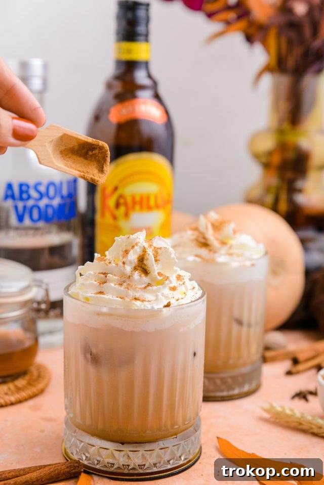 A close-up of a Pumpkin Spice White Russian garnished with pumpkin pie spice and a cinnamon stick, ready to be enjoyed.