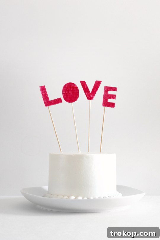 DIY Fringed Love Cake Topper for Valentine's Day or anniversaries, featuring delicate pink and red fringe spelling out 'LOVE' on a cake.
