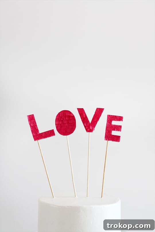 Close-up of a DIY Fringed Love Cake Topper, showcasing the layered tissue paper fringe texture and delicate craftsmanship.
