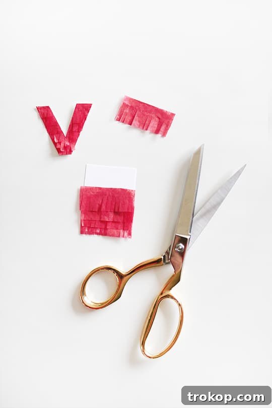 Handmade Fringed Love Cake Topper 4 Materials laid out for making a DIY fringe cake topper: tissue paper, scissors, cardstock, glue, and kabob sticks