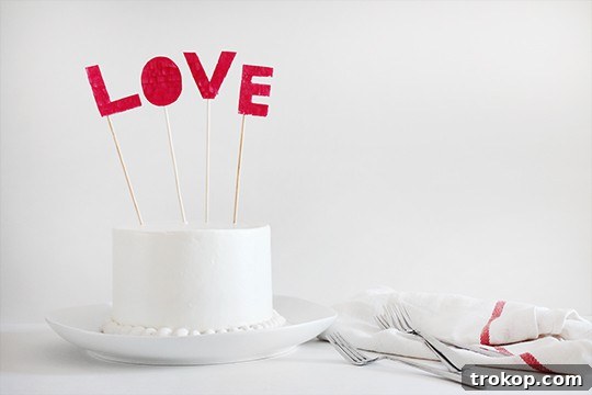 Close-up of the fringed letters of the 'LOVE' cake topper from an angle, highlighting the layered texture and vibrant colors.