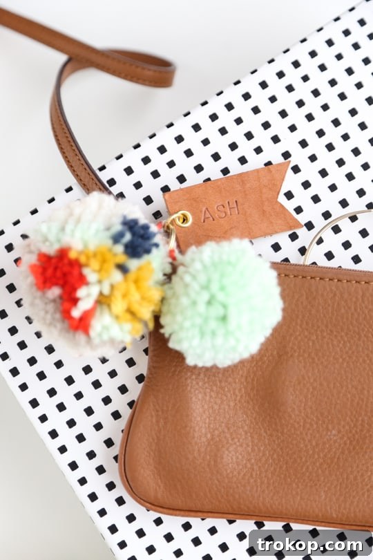 Playful Pom Pom Leather Bag Charms 3 Close-up of a handmade pom pom and leather luggage tag attached to travel bag