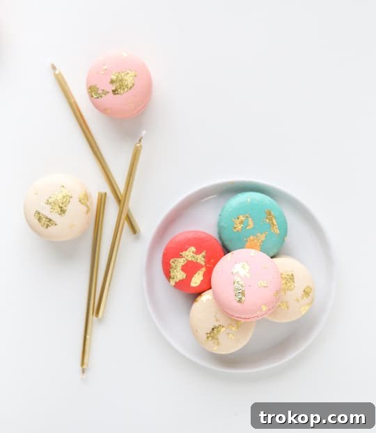 Close-up of golden macarons on a serving plate, highlighting the delicate gold leaf application