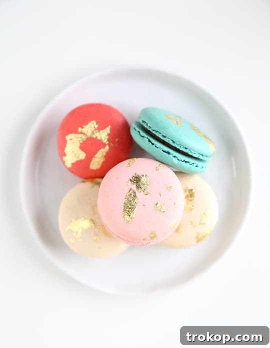 Assorted edible gold macarons showcasing various gold leaf patterns